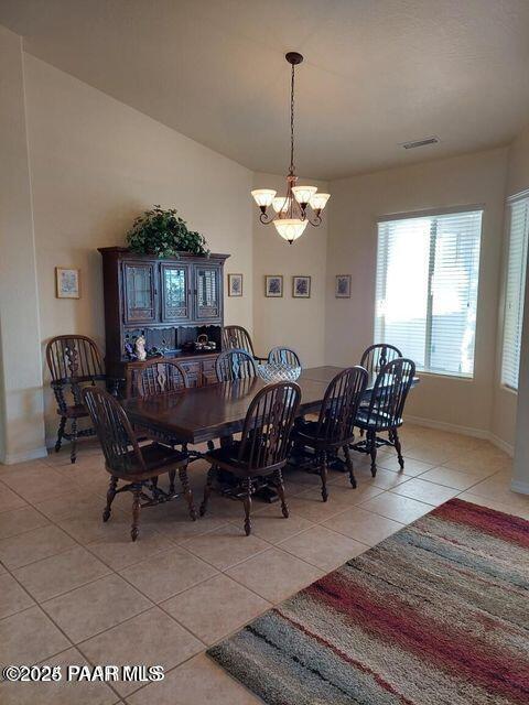 dining area featuring light tile patterned flooring, a notable chandelier, visible vents, and baseboards