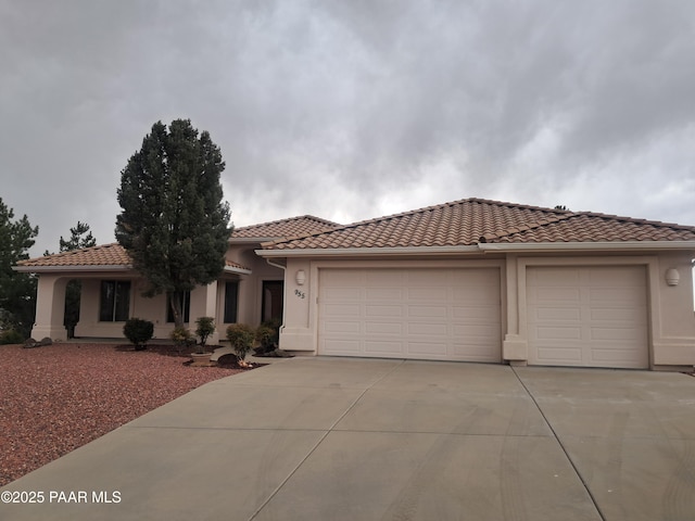 view of front of house featuring a garage, a tile roof, concrete driveway, and stucco siding