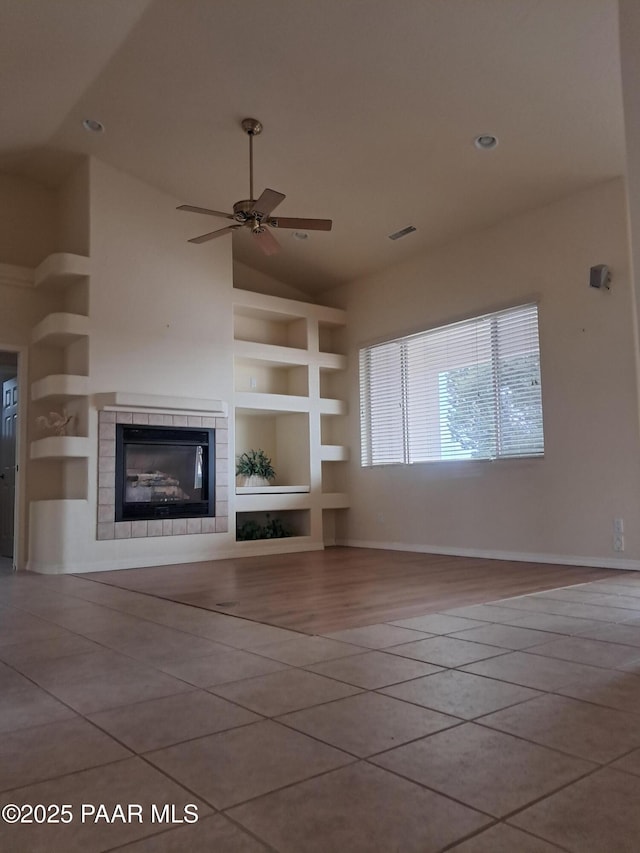 unfurnished living room featuring built in shelves, lofted ceiling, a ceiling fan, and tile patterned floors