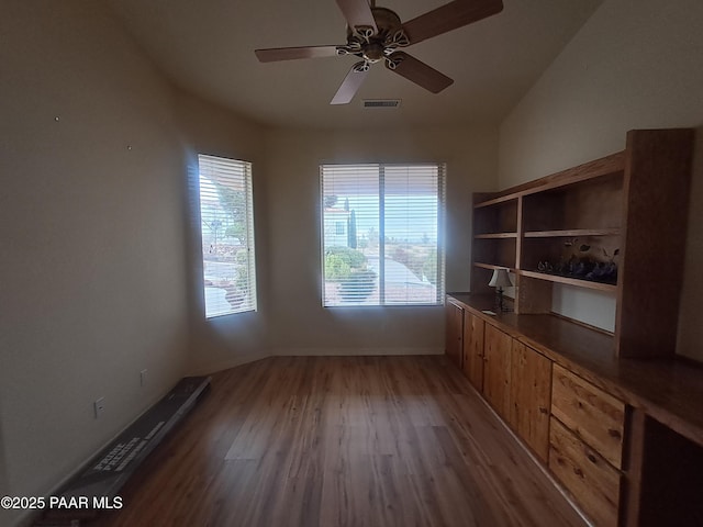 interior space featuring a ceiling fan, light wood-type flooring, visible vents, and baseboards