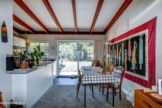 dining space featuring beamed ceiling and carpet