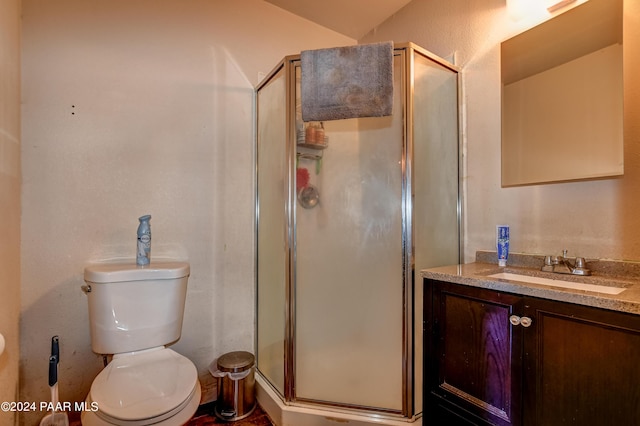bathroom with vanity, toilet, and a shower with door