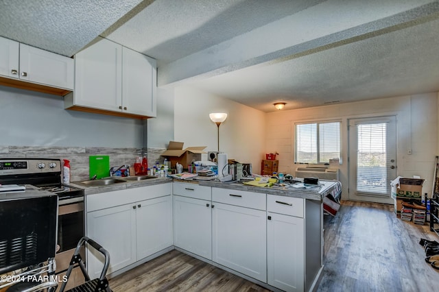kitchen with hardwood / wood-style floors, stainless steel range with electric cooktop, kitchen peninsula, sink, and white cabinetry
