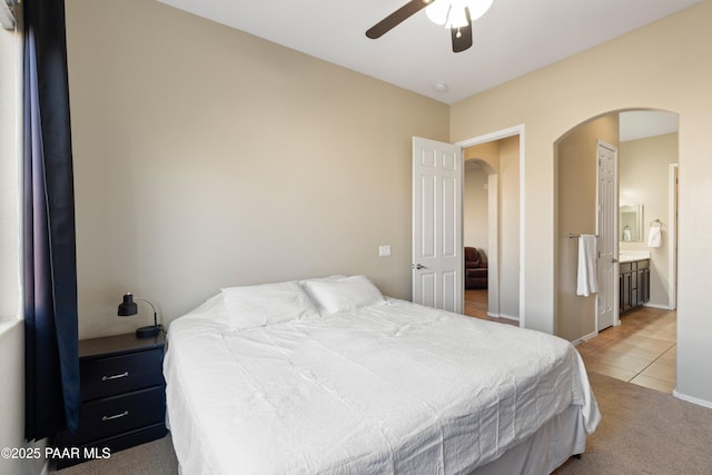 bedroom featuring connected bathroom, light tile patterned floors, and ceiling fan