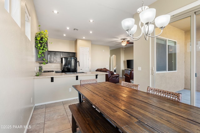 dining space featuring sink, ceiling fan with notable chandelier, and light tile patterned flooring