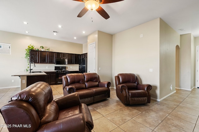 living room with sink, light tile patterned floors, and ceiling fan