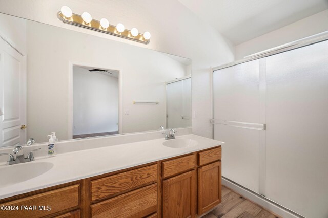 bathroom with hardwood / wood-style flooring, vanity, lofted ceiling, and walk in shower