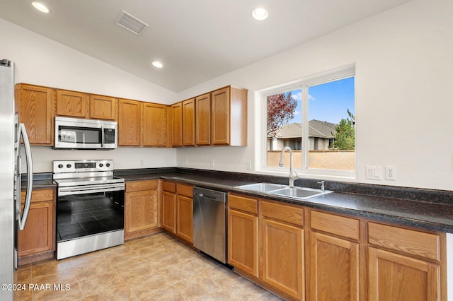 kitchen featuring light tile patterned floors, sink, appliances with stainless steel finishes, and vaulted ceiling