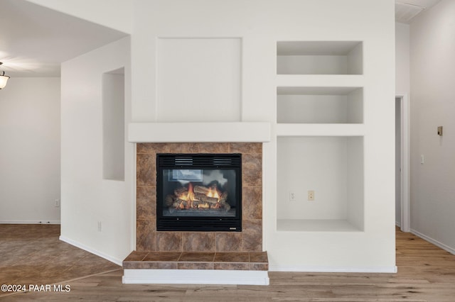 interior details featuring built in features, wood-type flooring, and a tiled fireplace