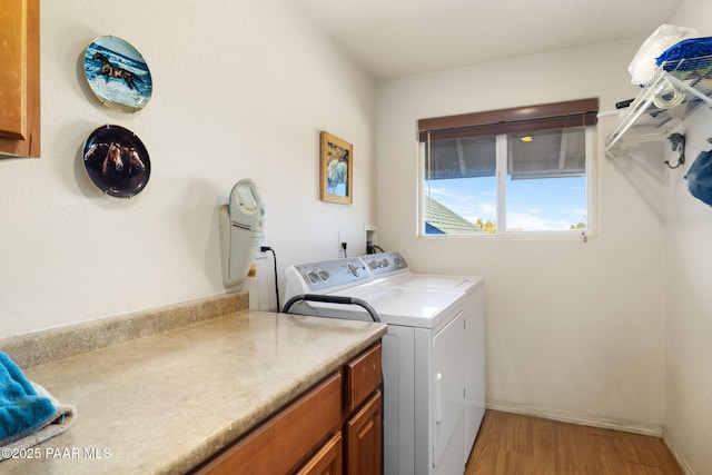 laundry room featuring cabinets, wood-type flooring, and washer and dryer