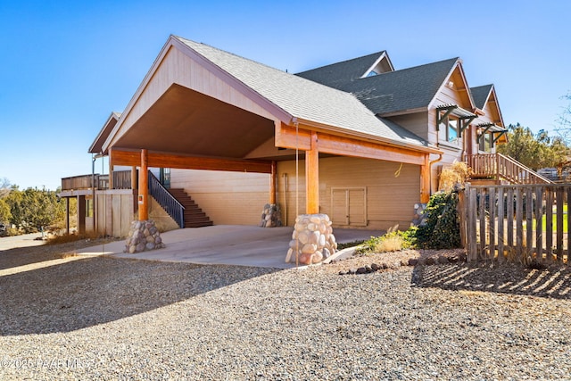 6850 N Harris Dr, Prescott, AZ 86305 - view of property exterior with stairway, an attached carport, driveway, roof with shingles, and fence
