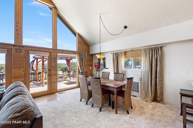 carpeted dining room featuring high vaulted ceiling and a healthy amount of sunlight