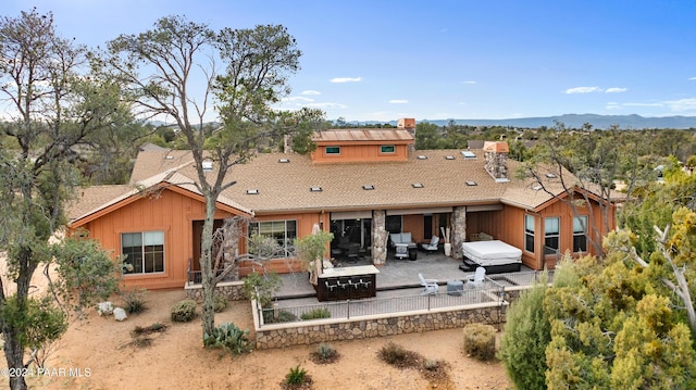 back of house featuring an outdoor hangout area, a mountain view, a patio, and a hot tub