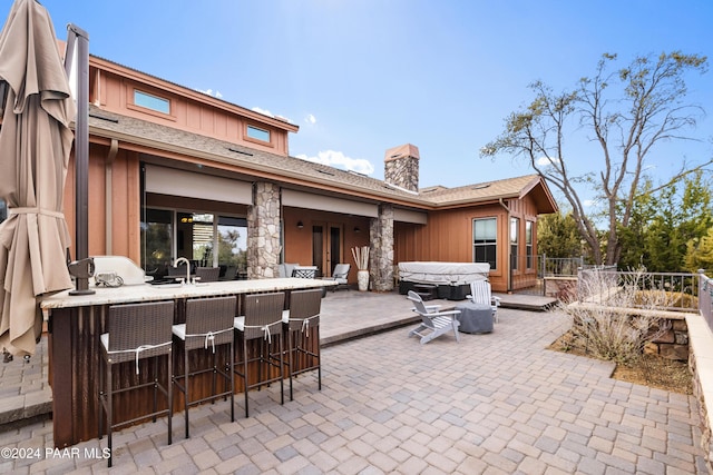 view of patio / terrace featuring an outdoor wet bar and a hot tub