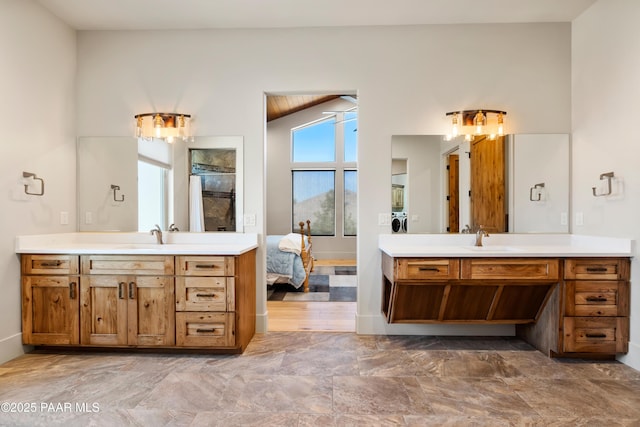 bathroom with a sink, washer / dryer, ensuite bath, and two vanities