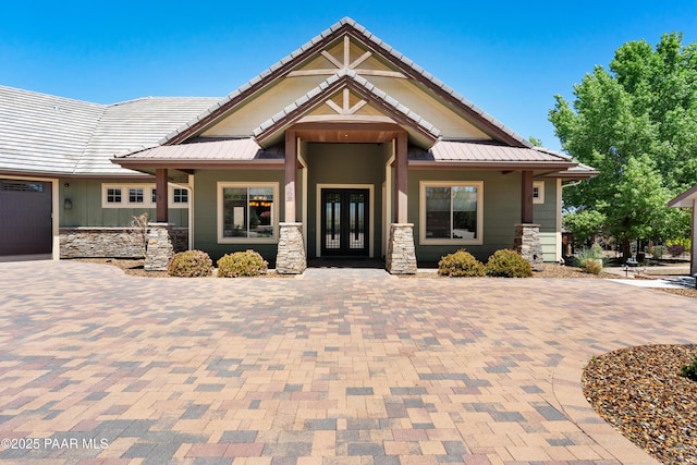 craftsman house with french doors, metal roof, and stone siding