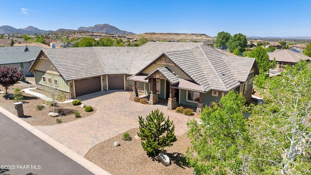 view of front of home featuring stone siding, a tiled roof, an attached garage, a mountain view, and driveway