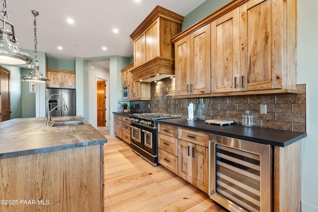 kitchen featuring dark countertops, light wood-type flooring, a sink, beverage cooler, and stainless steel appliances