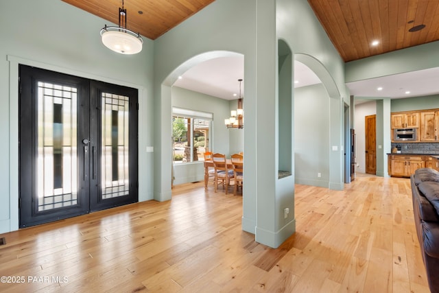 entrance foyer featuring arched walkways, recessed lighting, light wood-style flooring, and a notable chandelier