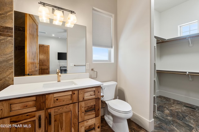 bathroom with a healthy amount of sunlight, baseboards, vanity, and toilet