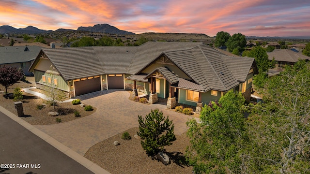 view of front of home featuring an attached garage, stone siding, a mountain view, a tiled roof, and driveway