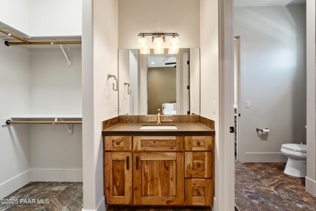 full bath with baseboards, toilet, and a walk in closet