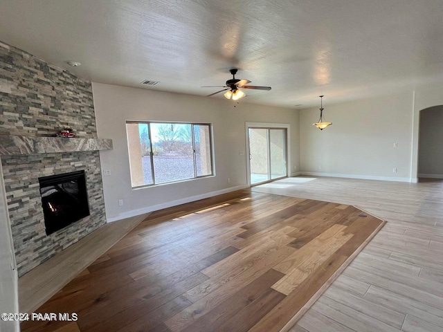 unfurnished living room with a fireplace, a textured ceiling, light hardwood / wood-style floors, and ceiling fan