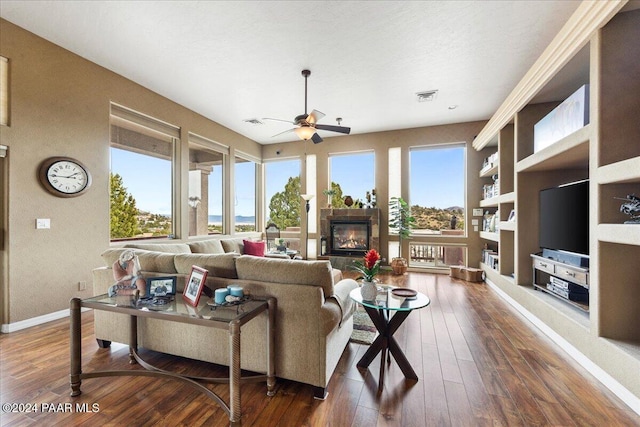 living room with dark hardwood / wood-style flooring, ceiling fan, plenty of natural light, and built in shelves