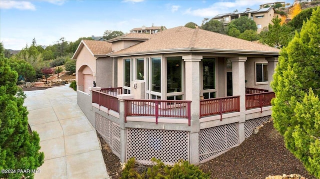 rear view of property featuring a wooden deck and a garage