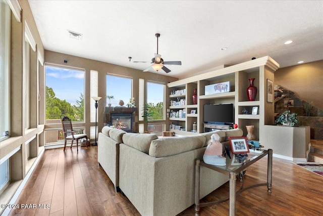 living room featuring baseboard heating, ceiling fan, and dark wood-type flooring