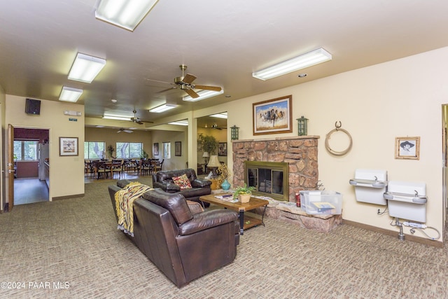 carpeted living room featuring a stone fireplace