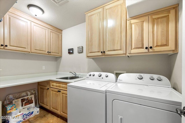 laundry room with sink, cabinets, a textured ceiling, washer and clothes dryer, and light tile patterned flooring