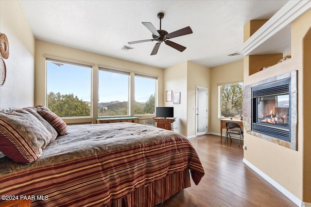 bedroom featuring ceiling fan, dark wood-type flooring, and a tiled fireplace