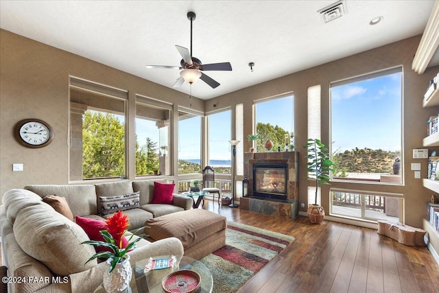 interior space featuring a tiled fireplace, a wealth of natural light, and dark hardwood / wood-style flooring