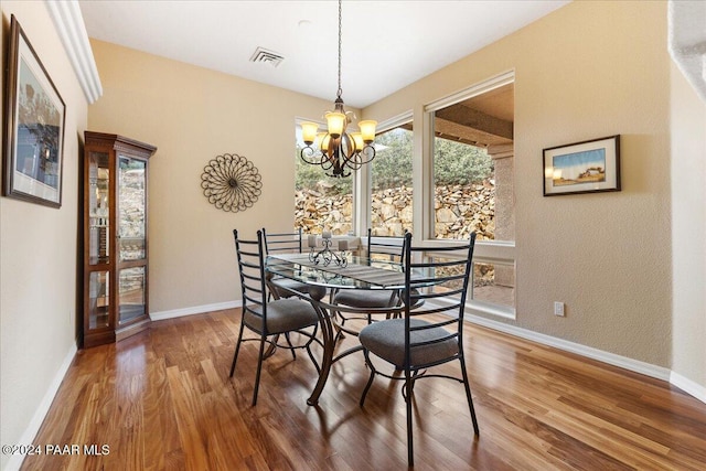 dining space featuring wood-type flooring and an inviting chandelier