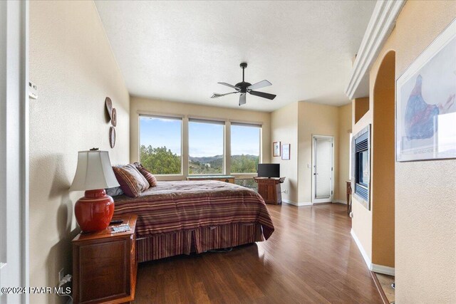 bedroom with a textured ceiling, ceiling fan, and dark hardwood / wood-style floors