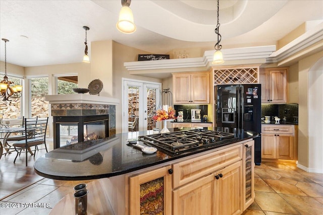 kitchen featuring black appliances, a multi sided fireplace, hanging light fixtures, decorative backsplash, and a kitchen island