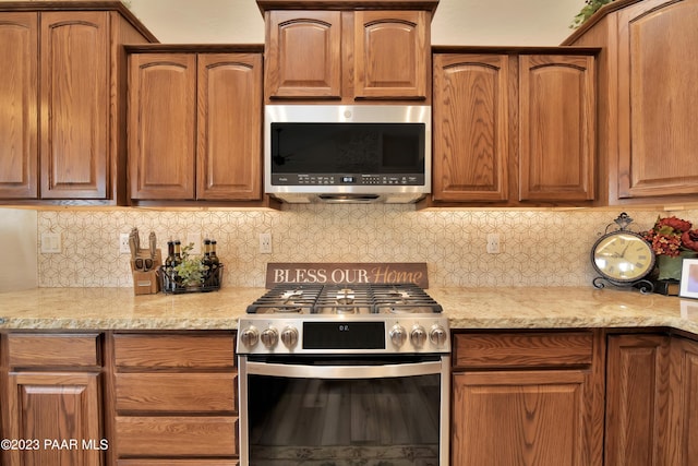 kitchen with light stone countertops, stainless steel appliances, and tasteful backsplash