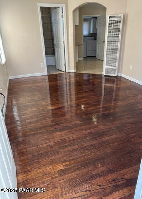 empty room with arched walkways, baseboards, and wood finished floors