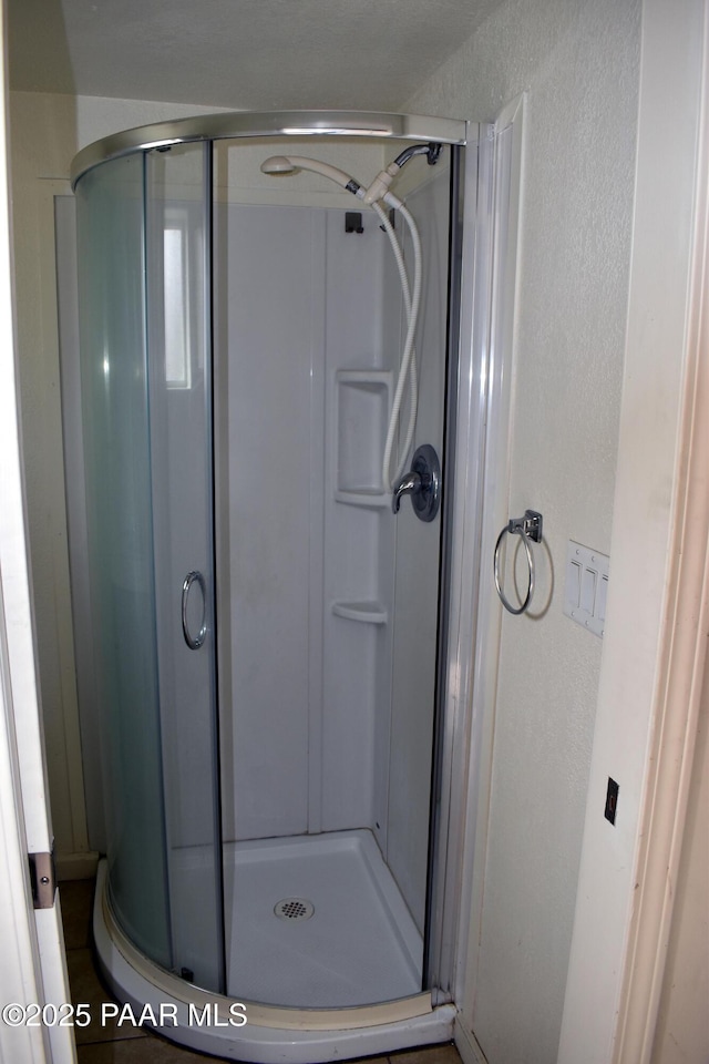 full bath featuring a stall shower and a textured wall