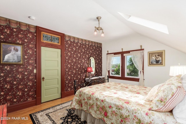 bedroom with hardwood / wood-style floors and vaulted ceiling with skylight