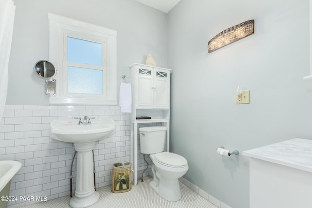 bathroom featuring tile patterned floors, toilet, and tile walls