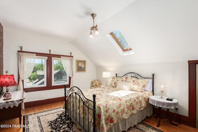 bedroom with hardwood / wood-style flooring and lofted ceiling with skylight