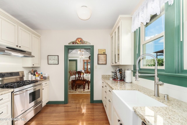 kitchen with light stone counters, light hardwood / wood-style flooring, stainless steel range with gas cooktop, and sink