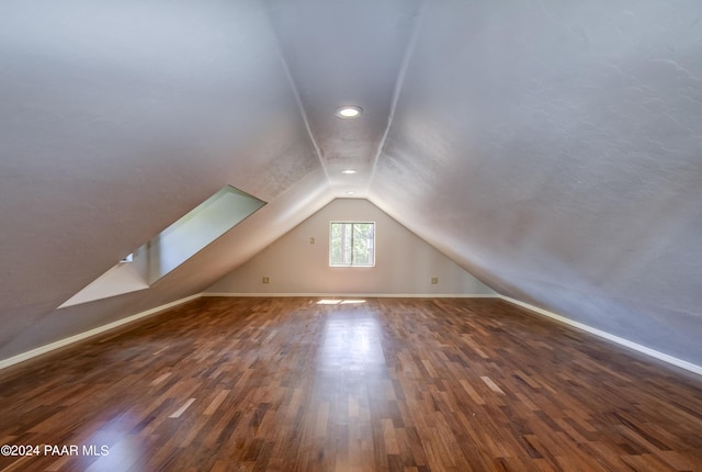 additional living space featuring dark hardwood / wood-style flooring and vaulted ceiling with skylight