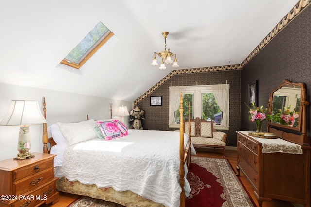 bedroom featuring lofted ceiling with skylight, hardwood / wood-style floors, and a notable chandelier