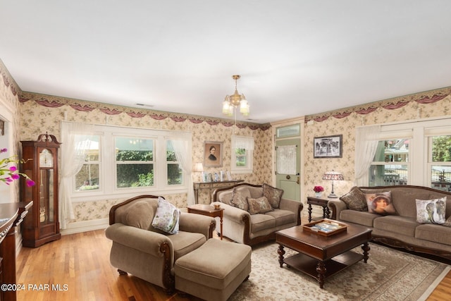 living room with plenty of natural light, a chandelier, and light hardwood / wood-style flooring