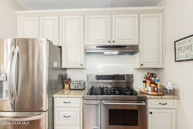 kitchen with decorative backsplash, appliances with stainless steel finishes, light stone counters, and cream cabinets