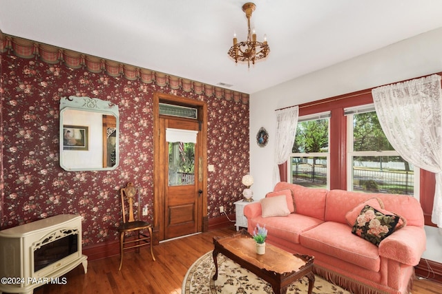 living room featuring hardwood / wood-style flooring, heating unit, and an inviting chandelier