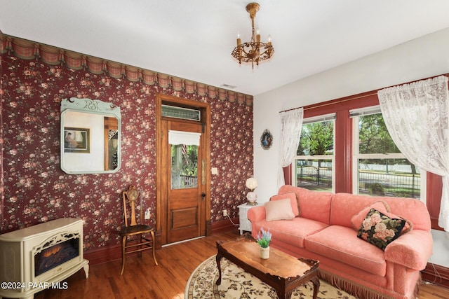 living room with heating unit, a chandelier, and hardwood / wood-style flooring